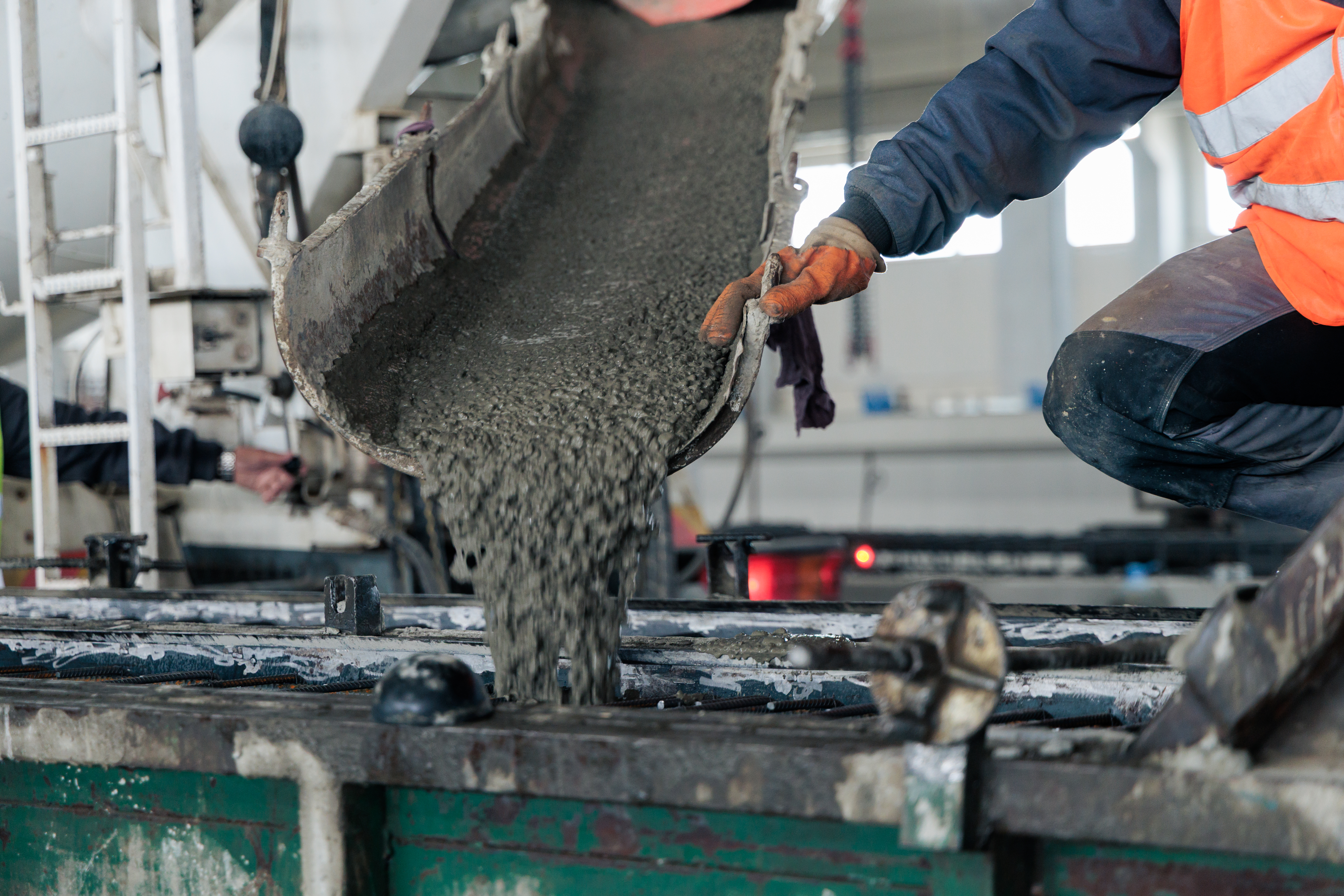 Construction worker pouring fresh concrete from a cement mixer into a mold at an industrial facility